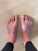 Die Füße einer Person stehen auf einem Holzboden.